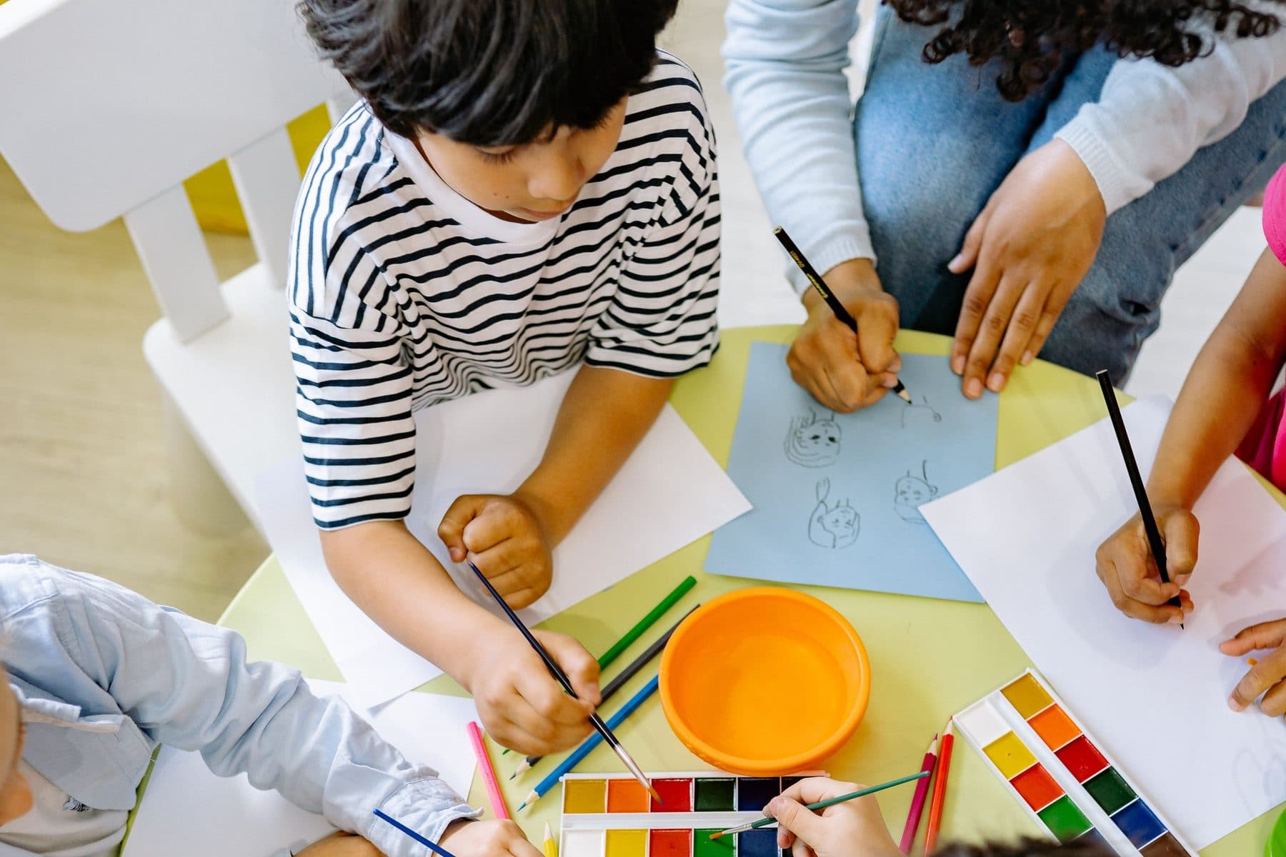 Children drawing and painting together around a classroom table